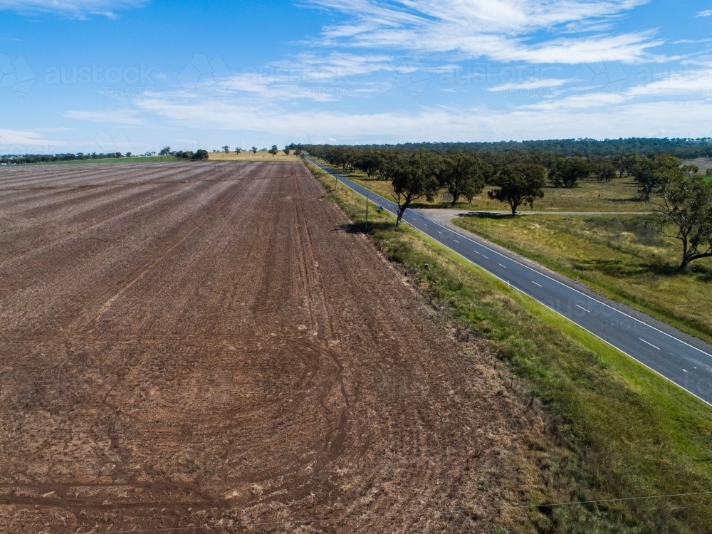 aerial view of harvested crop paddock and rural country road - Australian Stock Image