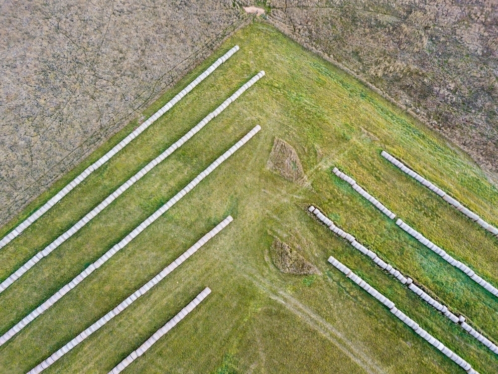 Aerial view of hay bales in rows at the corner of a paddock - Australian Stock Image