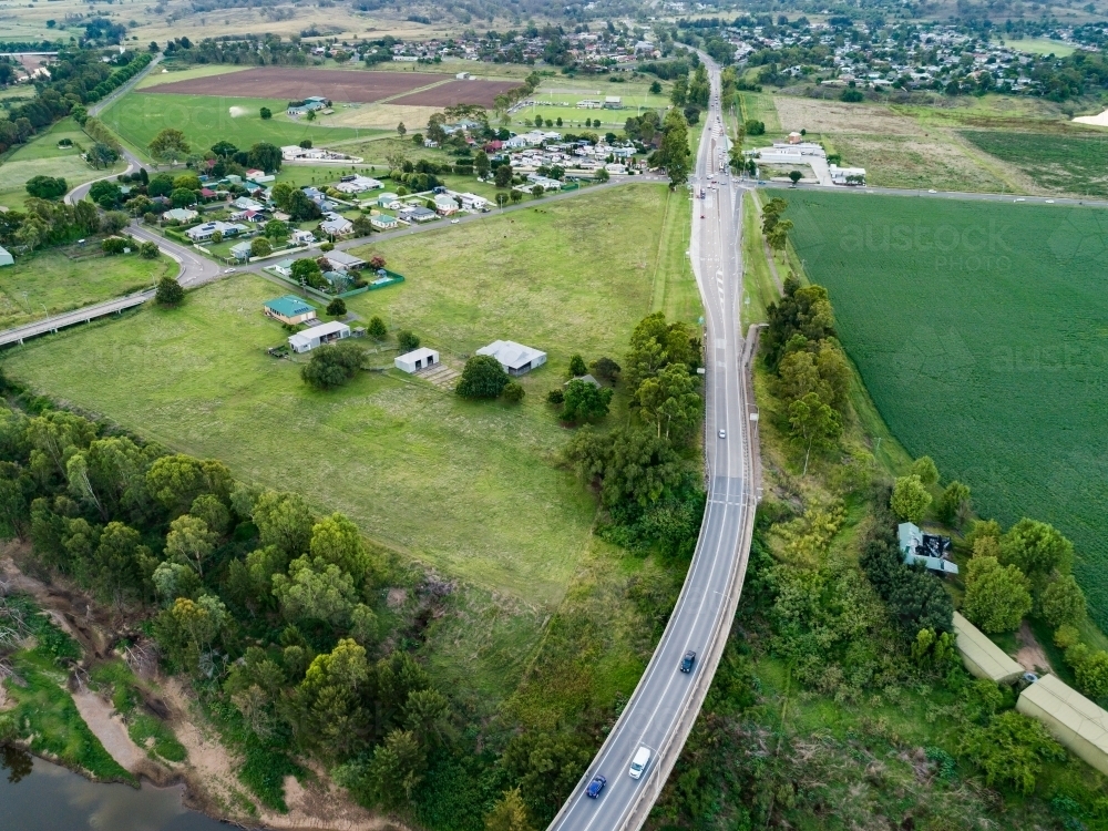 Aerial view of highway beside green paddock of alfalfa lucerne crop - Australian Stock Image