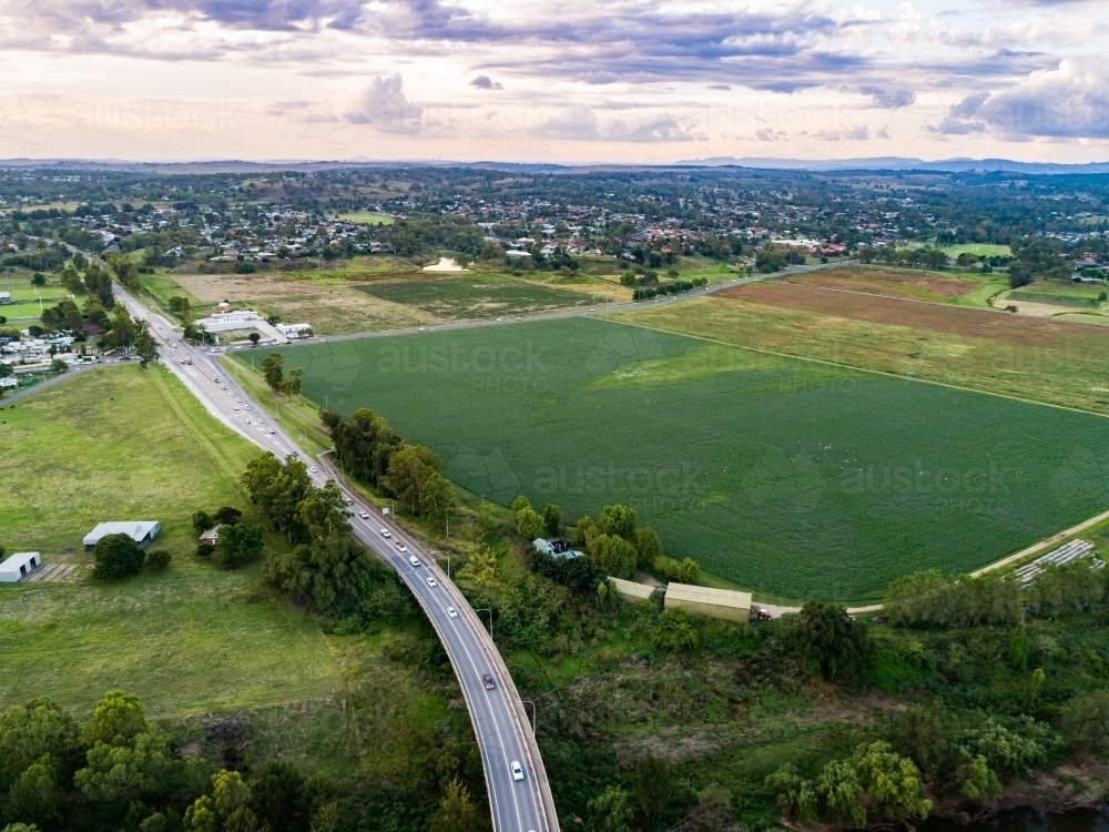 Aerial view of highway beside green paddock of alfalfa lucerne crop - Australian Stock Image