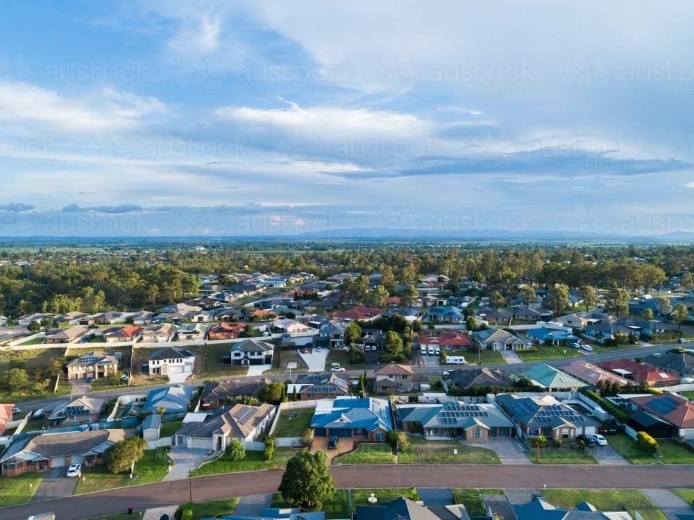 Aerial view of houses along street in town with green lawns - Australian Stock Image