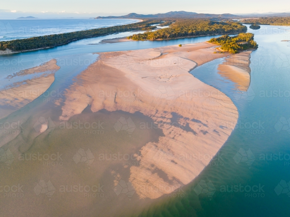 Aerial view of islands and water pools on tidal sand flats in early morning sunshine - Australian Stock Image