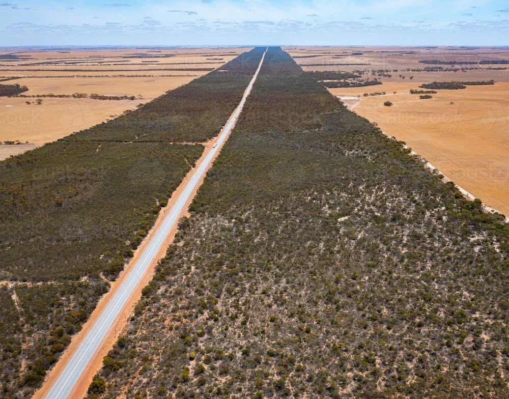 aerial view of long straight road edged by with remnant vegetation - Australian Stock Image