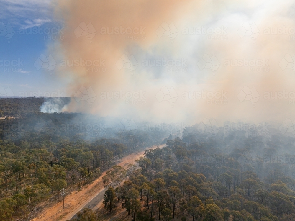 Aerial view of plumes of brown bushfire smoke rising from bushland - Australian Stock Image