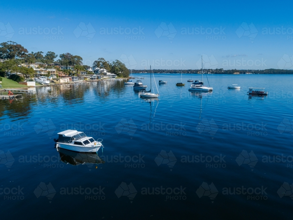 Aerial view of recreational boats in water of Lake Macquarie beside waterfront housing - Australian Stock Image