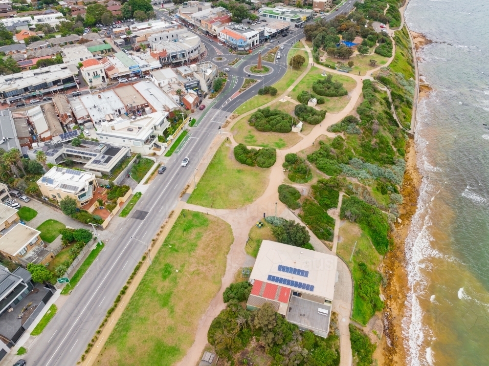 Aerial view of roads and roundabouts running through a shopping strip and coastal parkland - Australian Stock Image