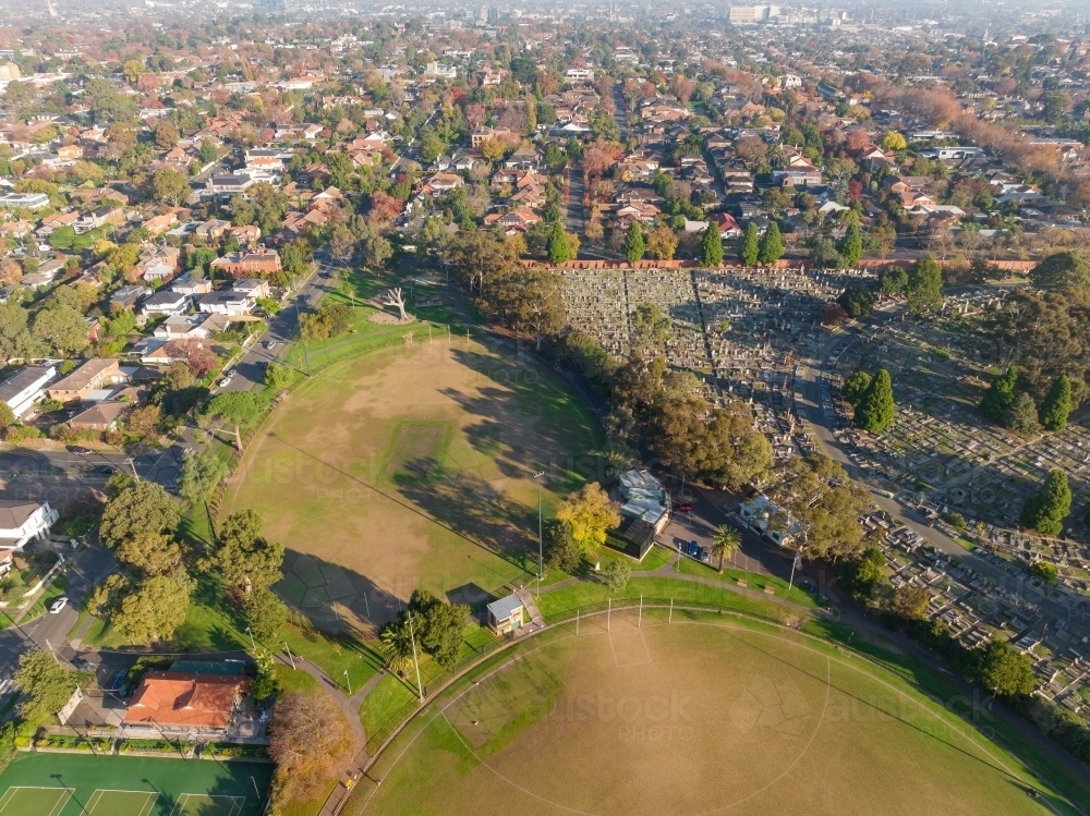 Aerial view of sporting ovals alongside a suburban cemetery - Australian Stock Image