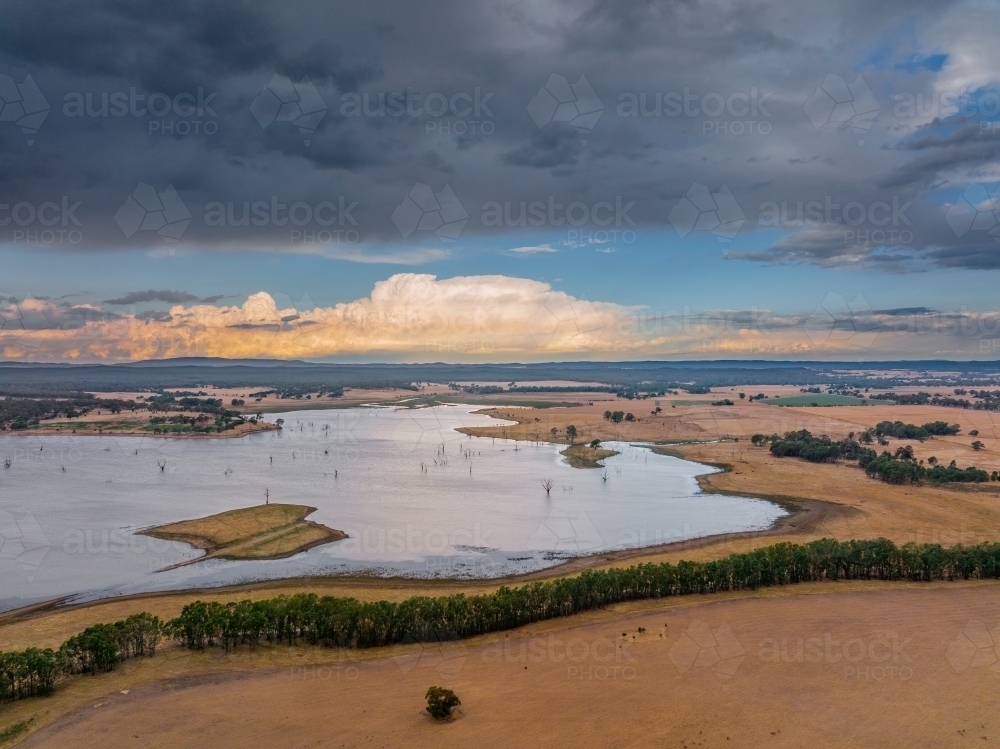 Aerial view of storm clouds and dramatic dark sky over an inland lake - Australian Stock Image