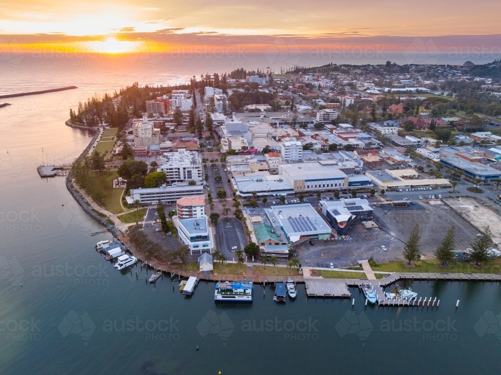 Aerial view of sunrise over a city waterfront on the the side of a river flowing out to the ocean - Australian Stock Image