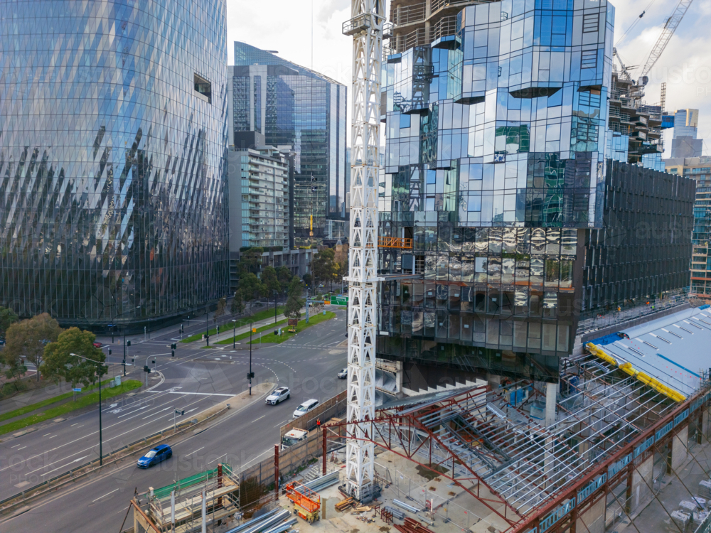 Aerial view of tall crane on a construction site in front of a city skyline - Australian Stock Image