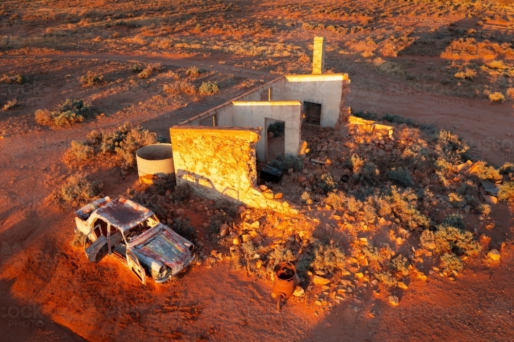 Aerial view of the ruins of an old brick cottage in a red outback landscape - Australian Stock Image