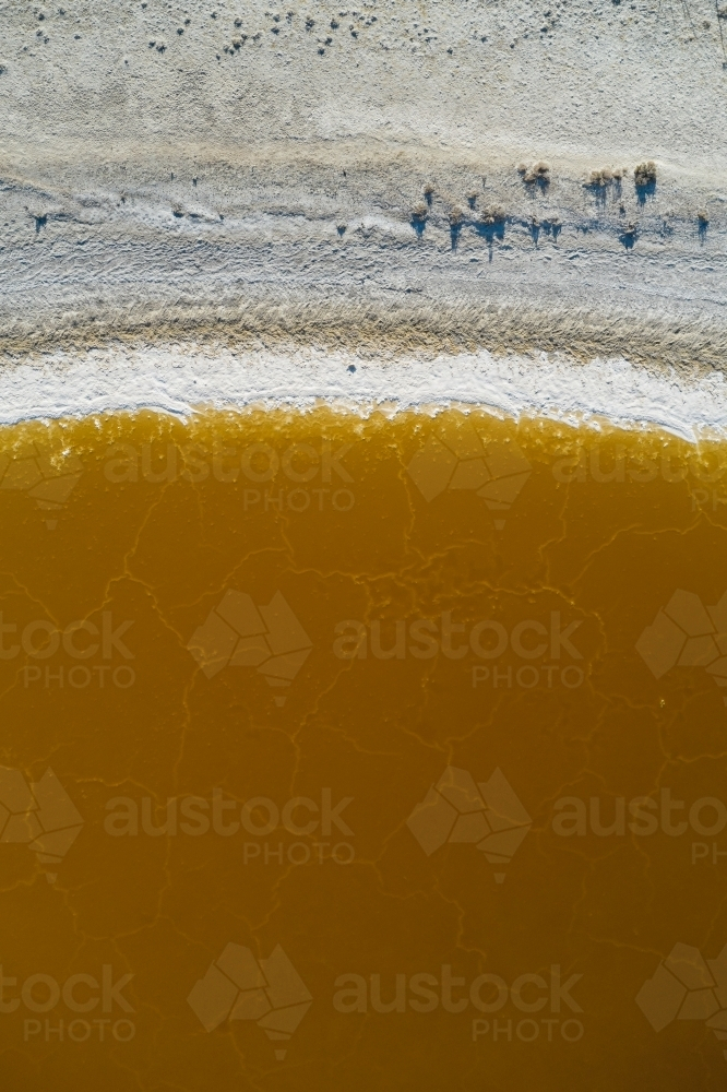 Aerial view of the shore of a brown salt lake in rural Western Australia. - Australian Stock Image