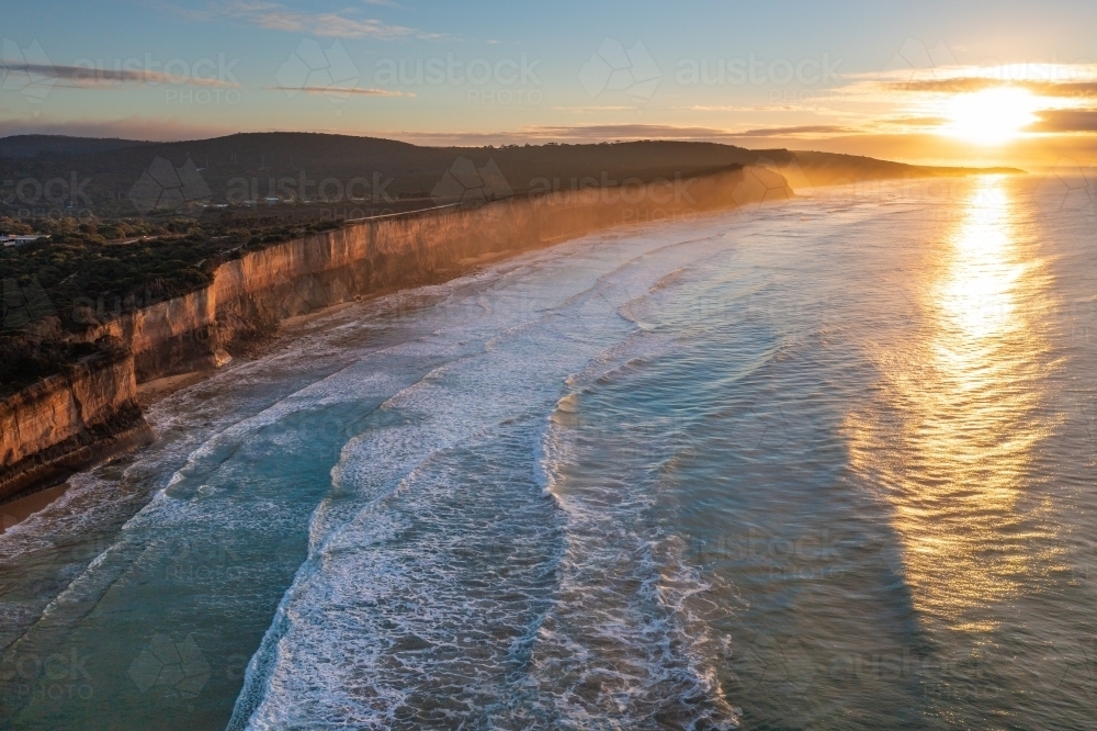 Aerial view of the sun rising over high coastal cliffs and endless waves - Australian Stock Image