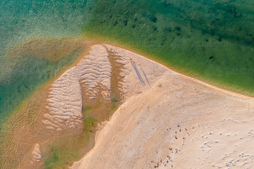 Aerial view of tiny figures walking on an isolated sandy beach - Australian Stock Image