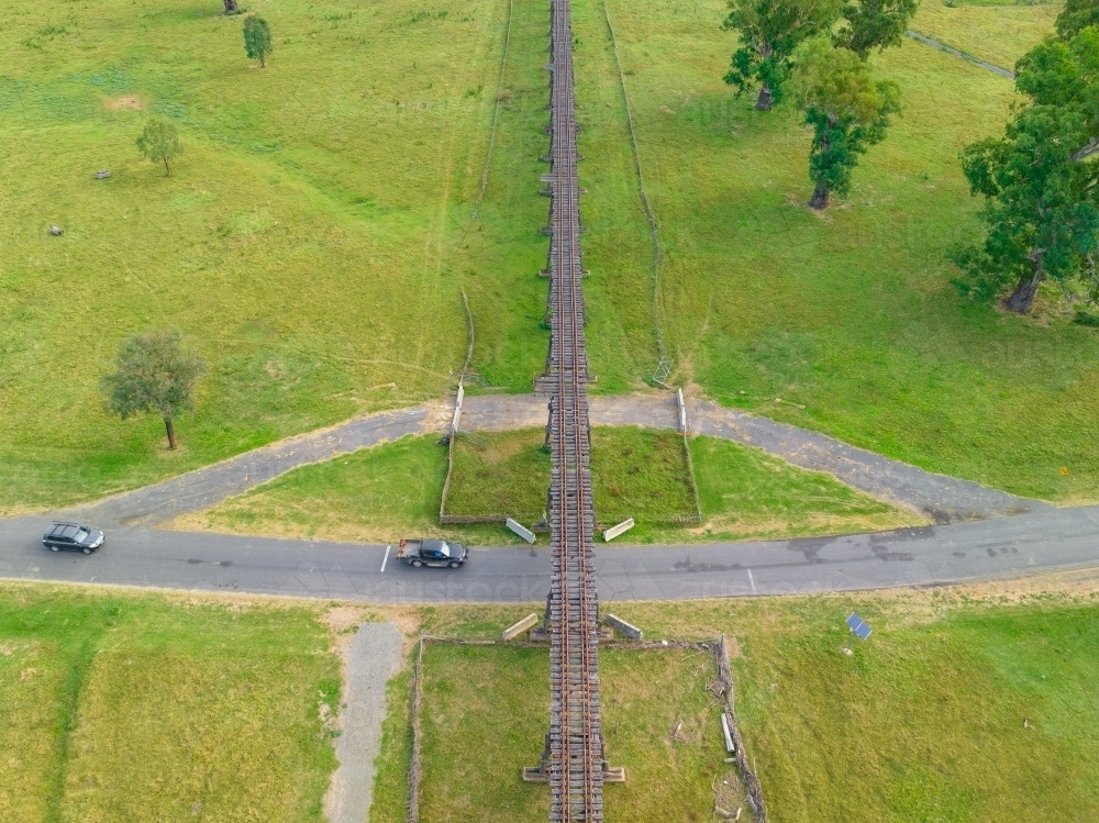 Aerial view of traffic on a country road passing under an abandoned railway viaduct - Australian Stock Image