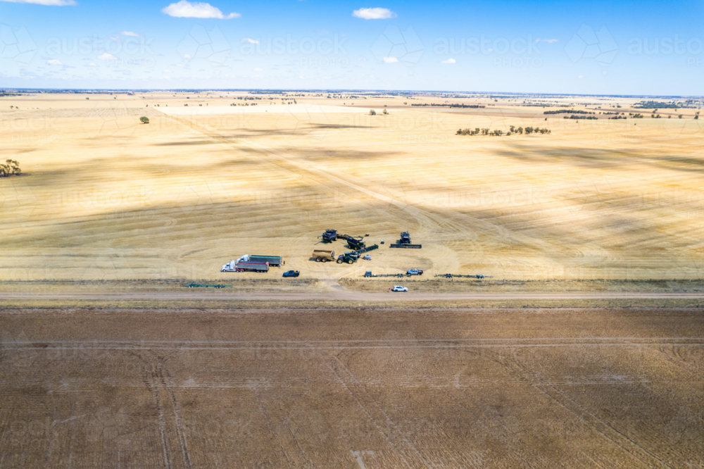 Aerial view of transport trucks and combine harvester on the field. - Australian Stock Image