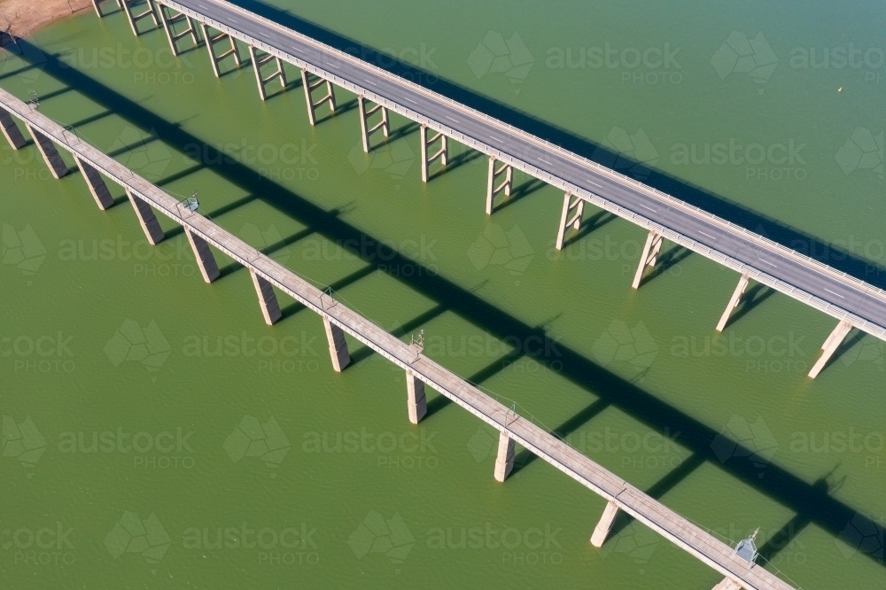 Aerial view of two parallel bridges casting shadows over the water of  large lake - Australian Stock Image