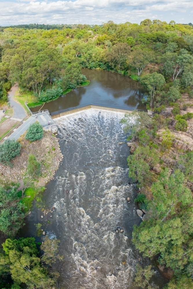 Aerial view of water rushing over a waterfall and down a river - Australian Stock Image