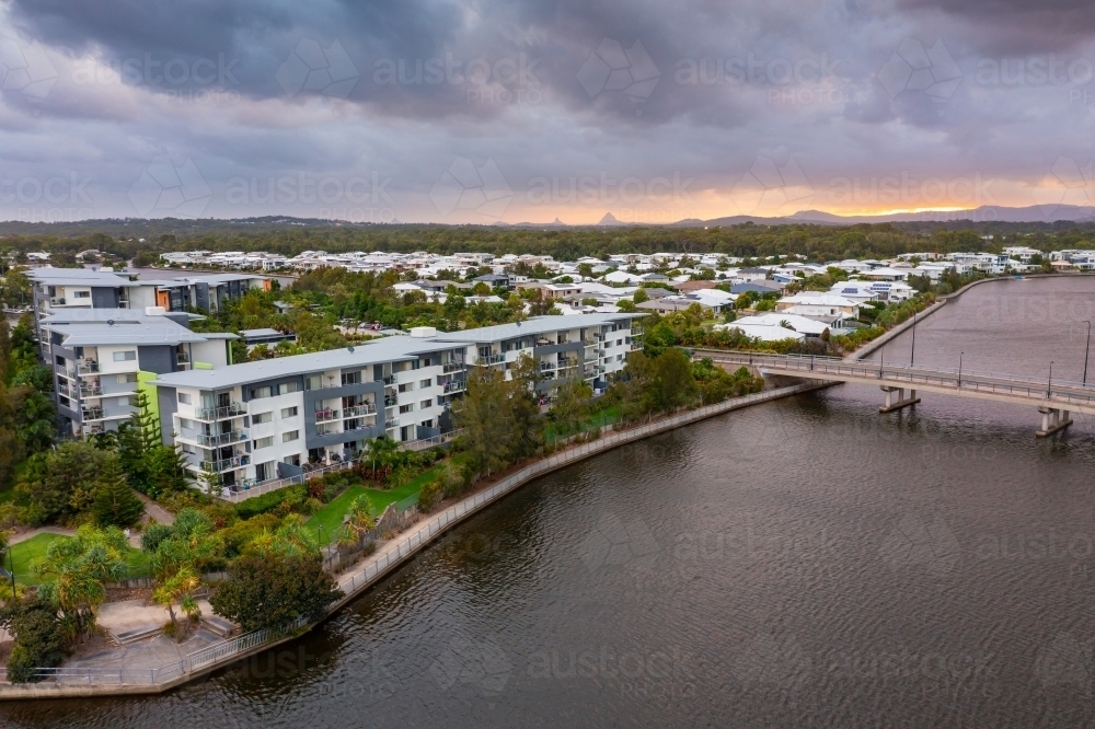 Aerial view of waterfront accommodation and a bridge over a canal under a dull sunset sky - Australian Stock Image