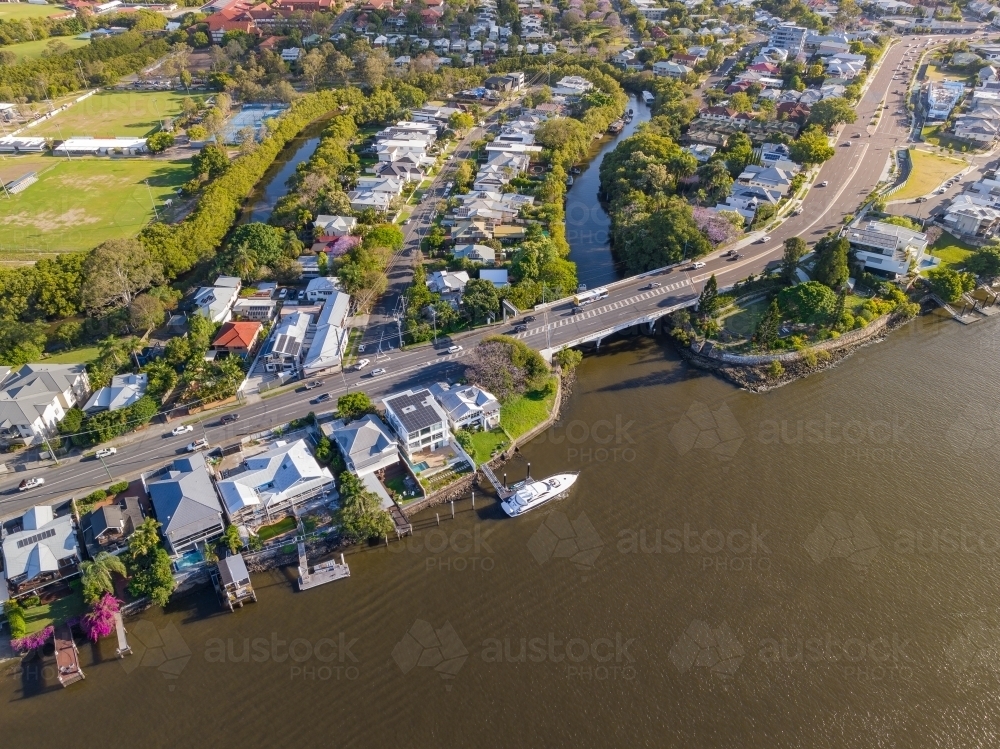 Aerial view of waterfront real estate on a river bank alongside a large bridge - Australian Stock Image