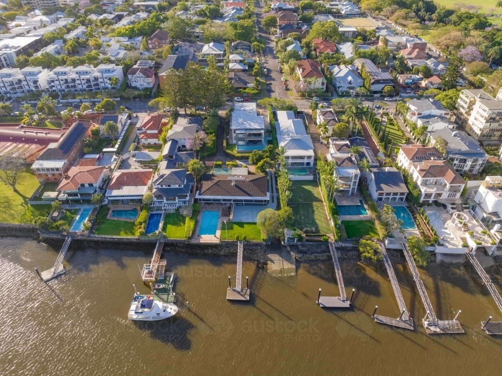 Aerial view of waterfront real estate with jetties and swimming pools on a river bank - Australian Stock Image