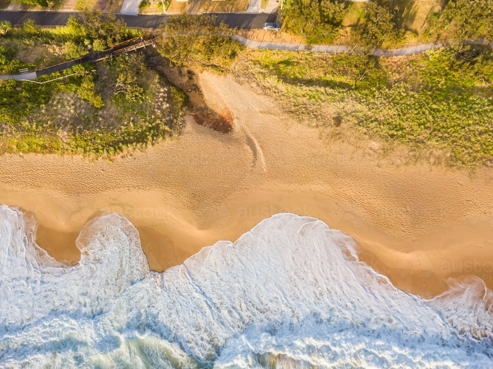 Aerial view of waves breaking on a sandy beach - Australian Stock Image