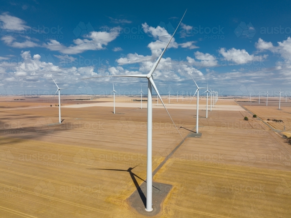 Aerial view of wind turbines scattered over rural farmland - Australian Stock Image