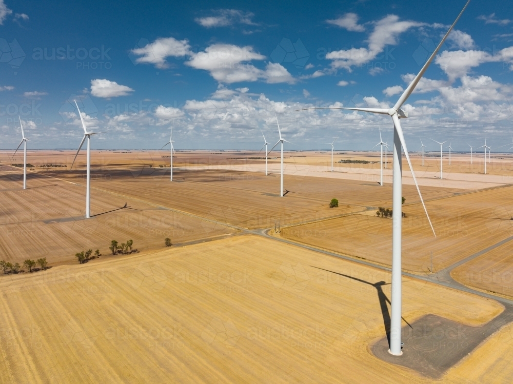 Aerial view of wind turbines scattered over rural farmland - Australian Stock Image