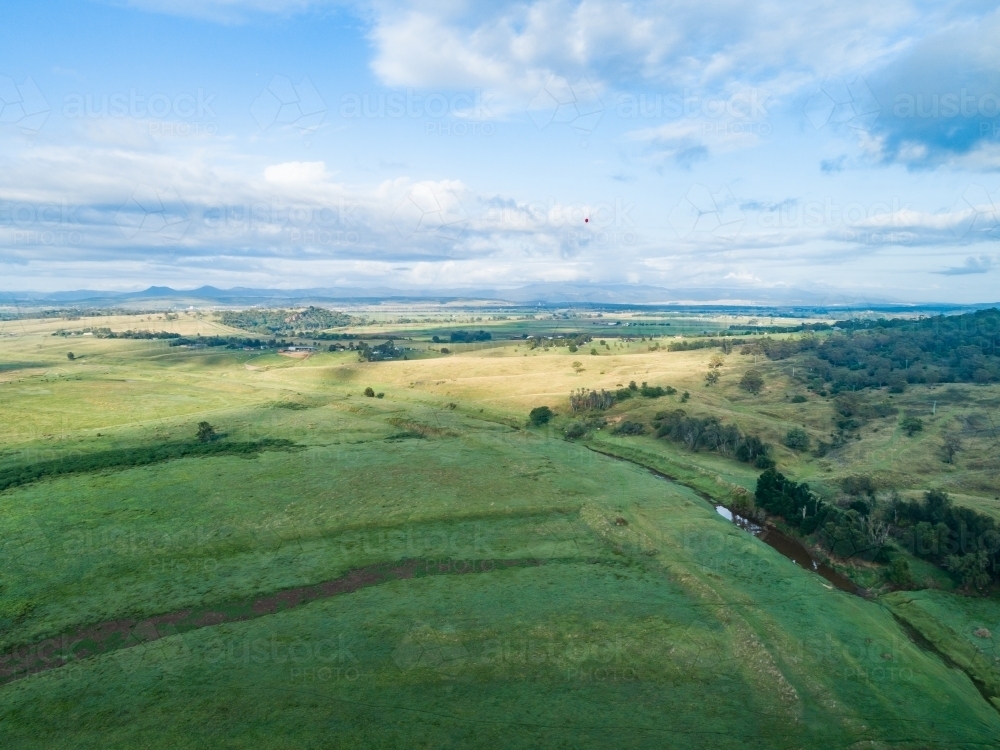 Aerial view over green land of farm paddocks in morning light during good season - Australian Stock Image