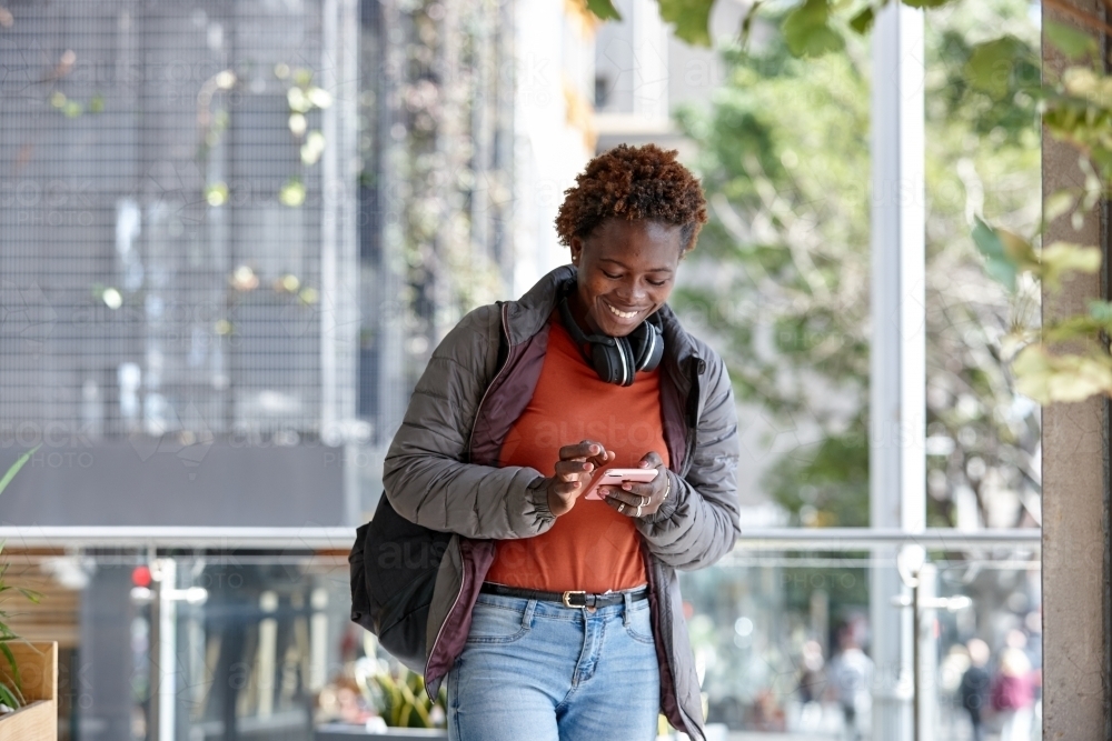 African woman having fun in city checking mobile phone - Australian Stock Image