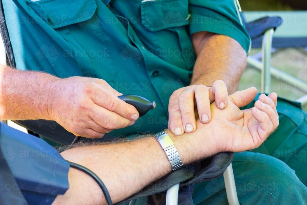 Ambulance officer checking pulse or blood pressure of patient - Australian Stock Image