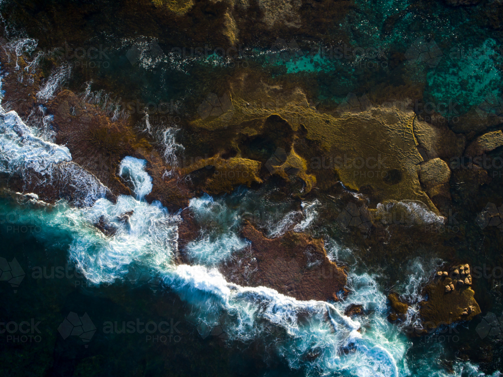 An aerial view exposing shapes in an exposed reef bed on the edge of the ocean - Australian Stock Image