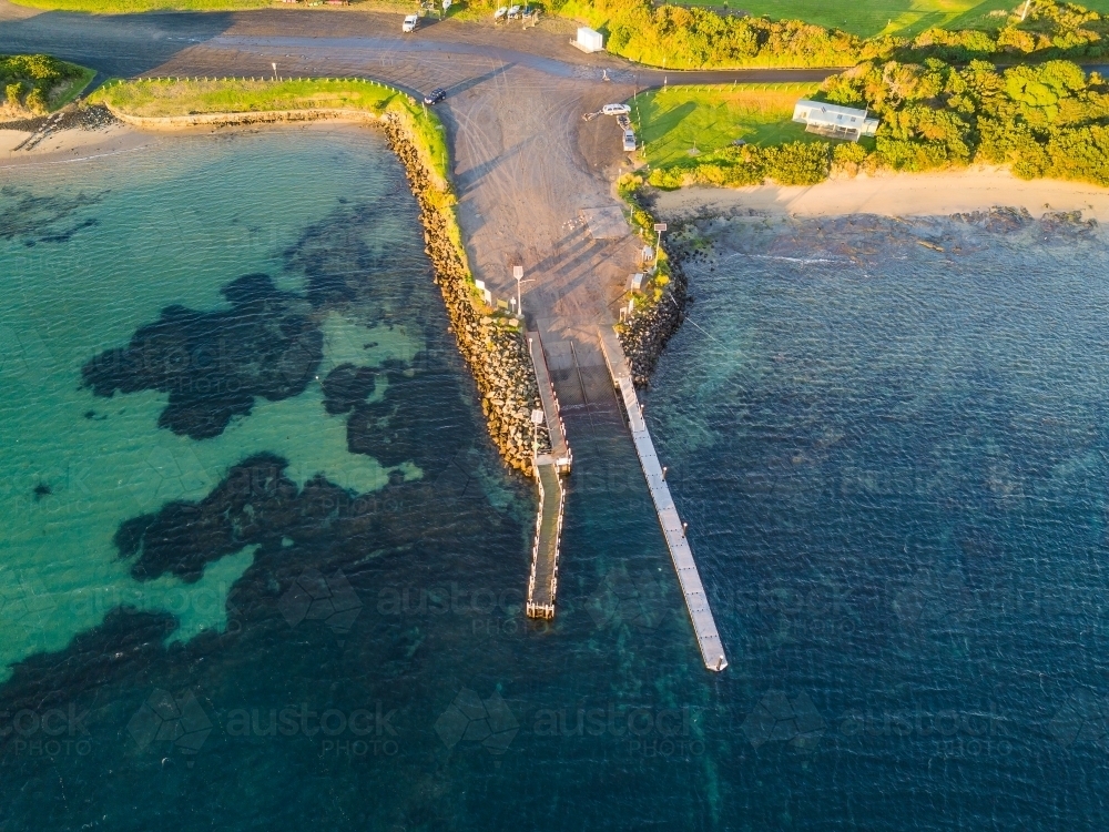 An aerial view of a boat ramp and jetty at a coastal marina. - Australian Stock Image