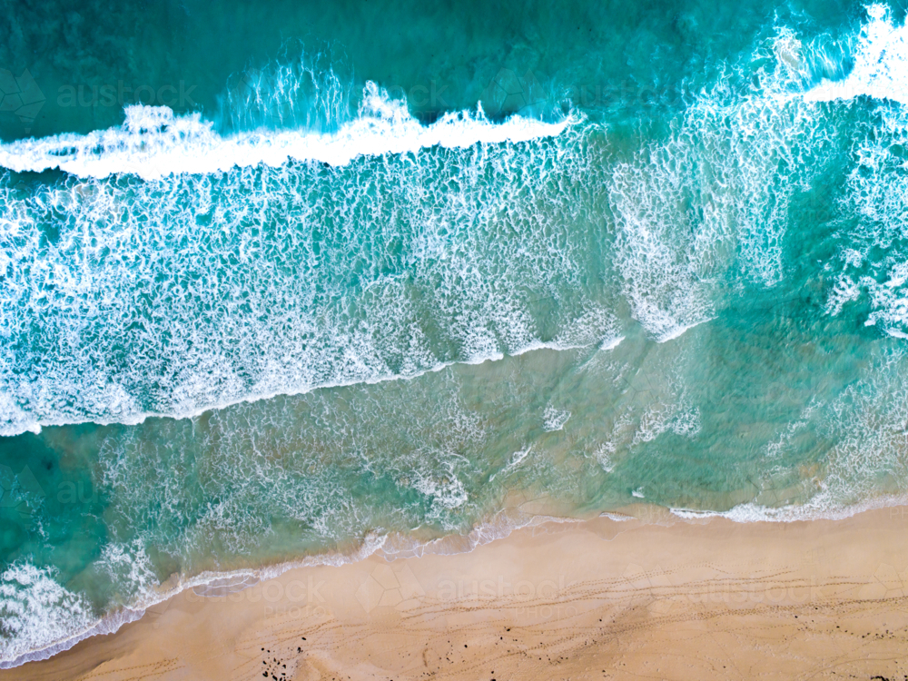 An aerial view of waves rolling to the shoreline - Australian Stock Image