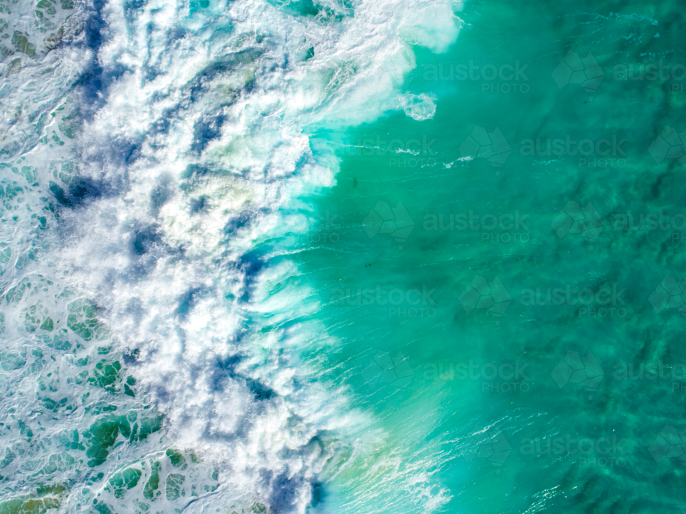 An aqua blue wave crashing over crystal clear water - Australian Stock Image