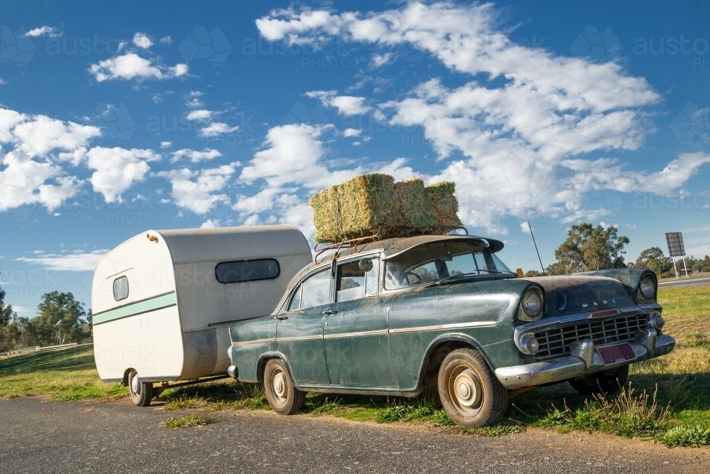 An old Holden and caravan parked on the roadside - Australian Stock Image