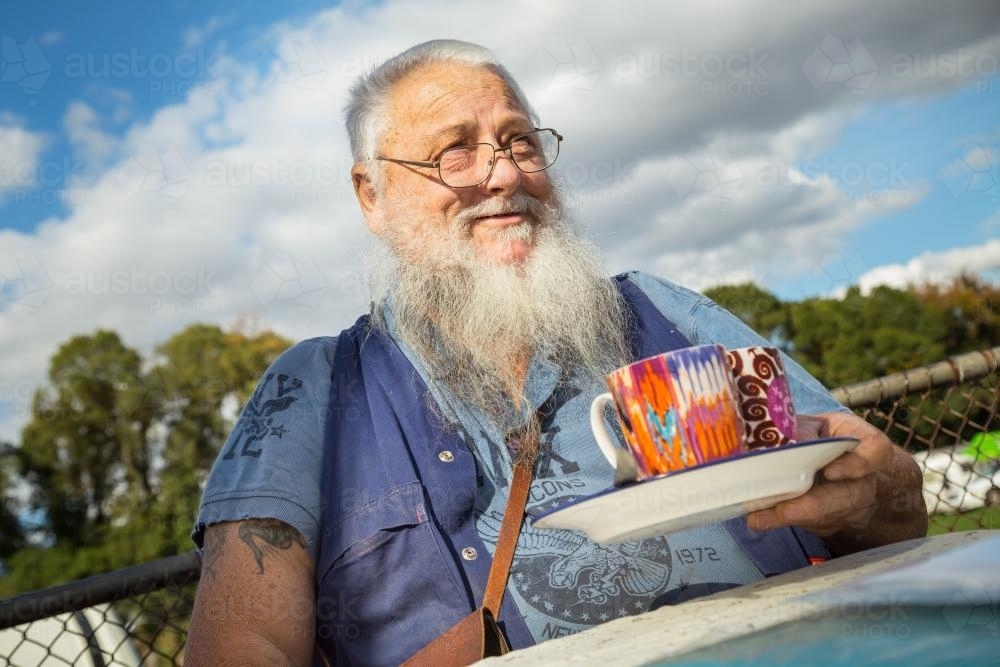 An old man holding coffee mugs - Australian Stock Image