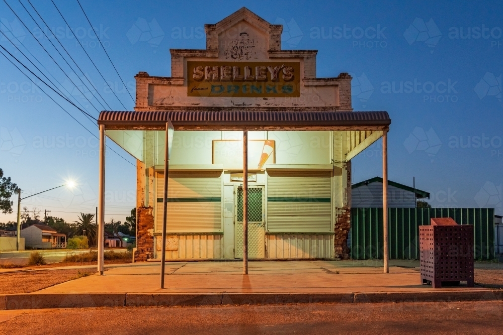 An old style corner milk bar with a veranda at twilight under street lights - Australian Stock Image