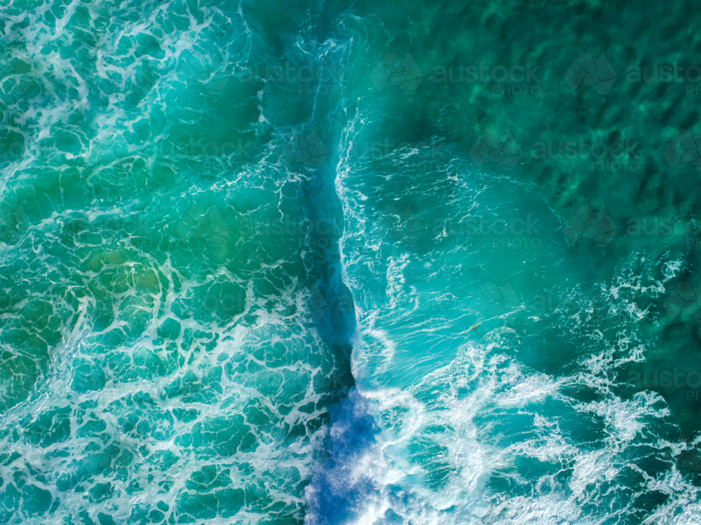 Aqua hues in the ocean are broken by the beginnings of a crashing wave - Australian Stock Image