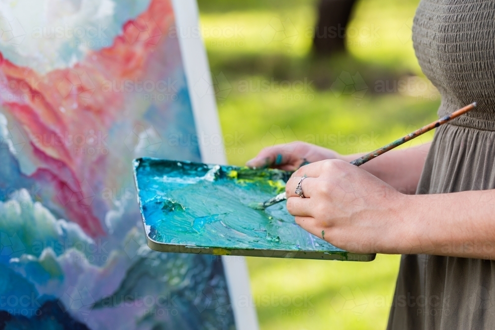 Artist holding messy paint pallet tray for mixing colours - Australian Stock Image