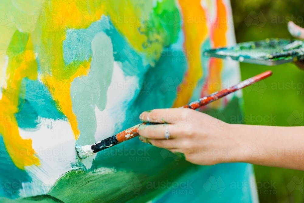 Artist with brush beginning an acrylic painting on canvase - Australian Stock Image