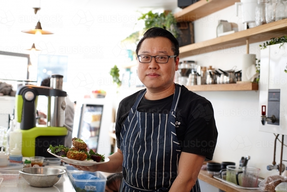 Asian chef working in kitchen at organic food cafe - Australian Stock Image