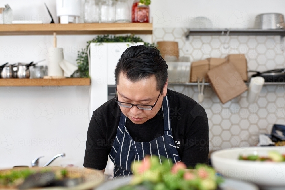 Asian chef working in kitchen at organic food cafe - Australian Stock Image