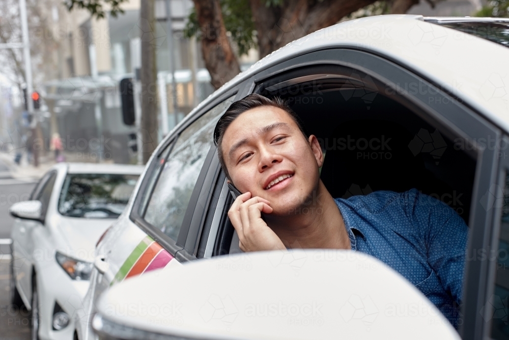 Asian man in parked vehicle looking out window - Australian Stock Image