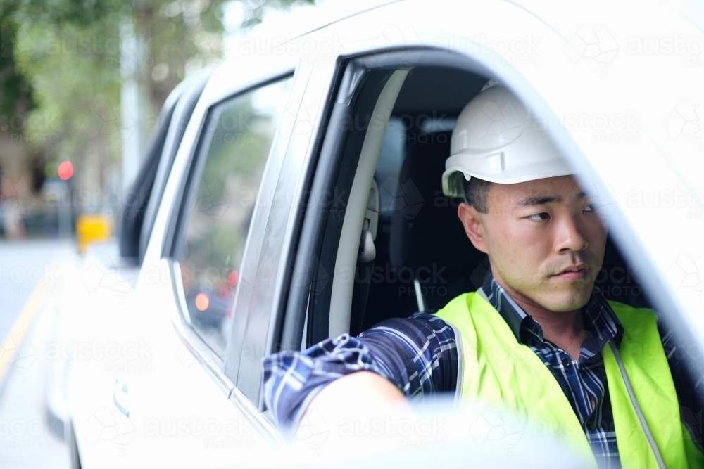 Asian man wearing hard hat in car - Australian Stock Image