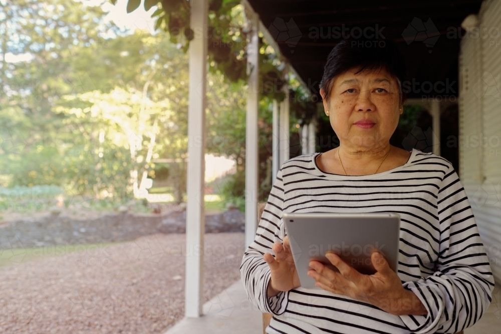 Asian senior woman using tablet - Australian Stock Image