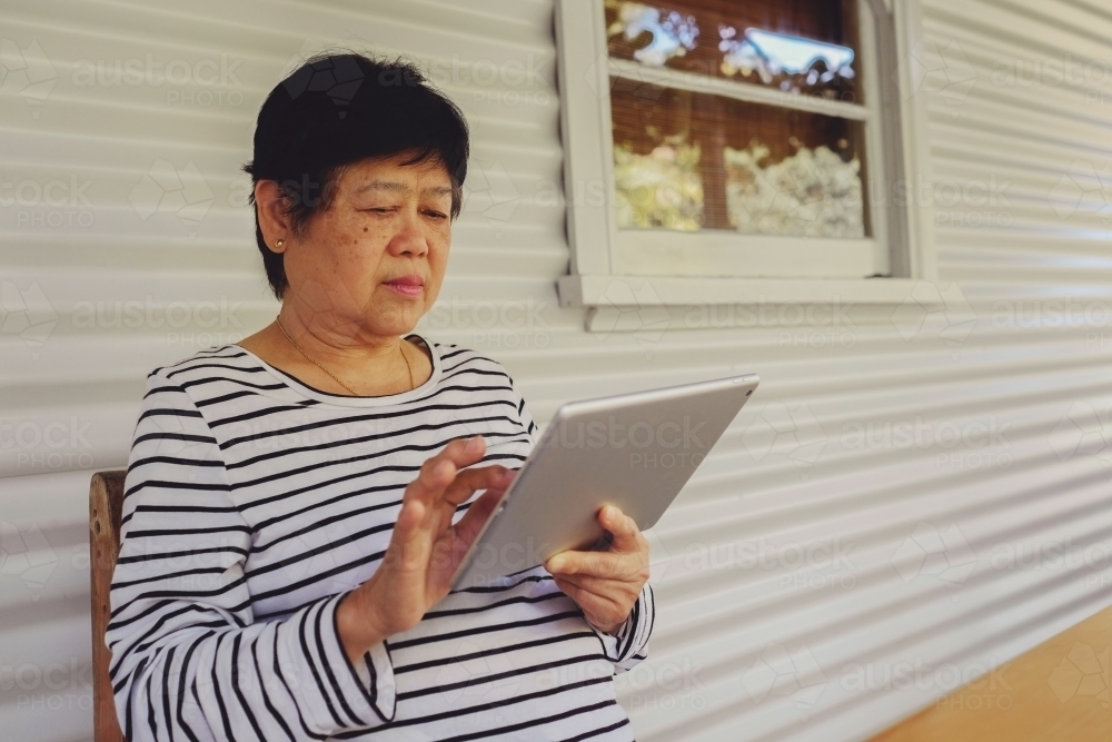 Asian senior woman using tablet - Australian Stock Image