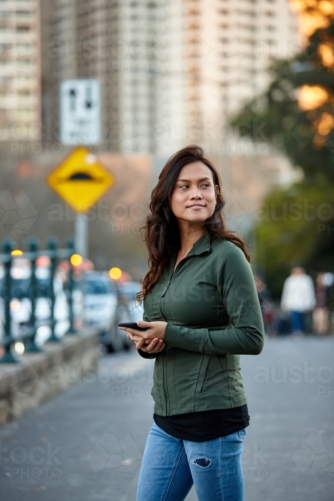 Asian woman at taxi stand with mobile phone - Australian Stock Image