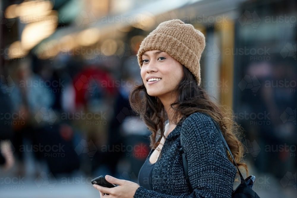 Asian woman getting off train at station with mobile phone - Australian Stock Image