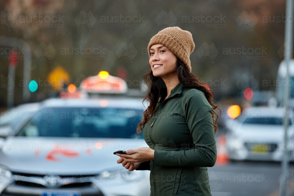 Asian woman looking for a taxi with mobile phone - Australian Stock Image